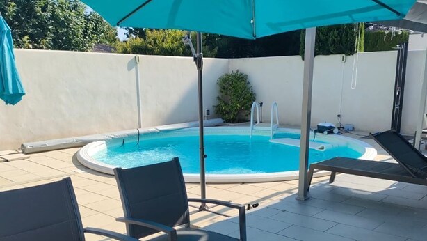 Ett utomhusområde med plats för att äta, komplett med en pool, stolar och ett bord där mat och dryck är uppdukat.