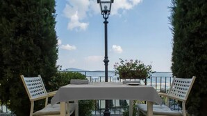An outdoor dining area with a table and chairs, a street lamp, and a view of the sea. - Standard Double or Twin Room (Toscana)