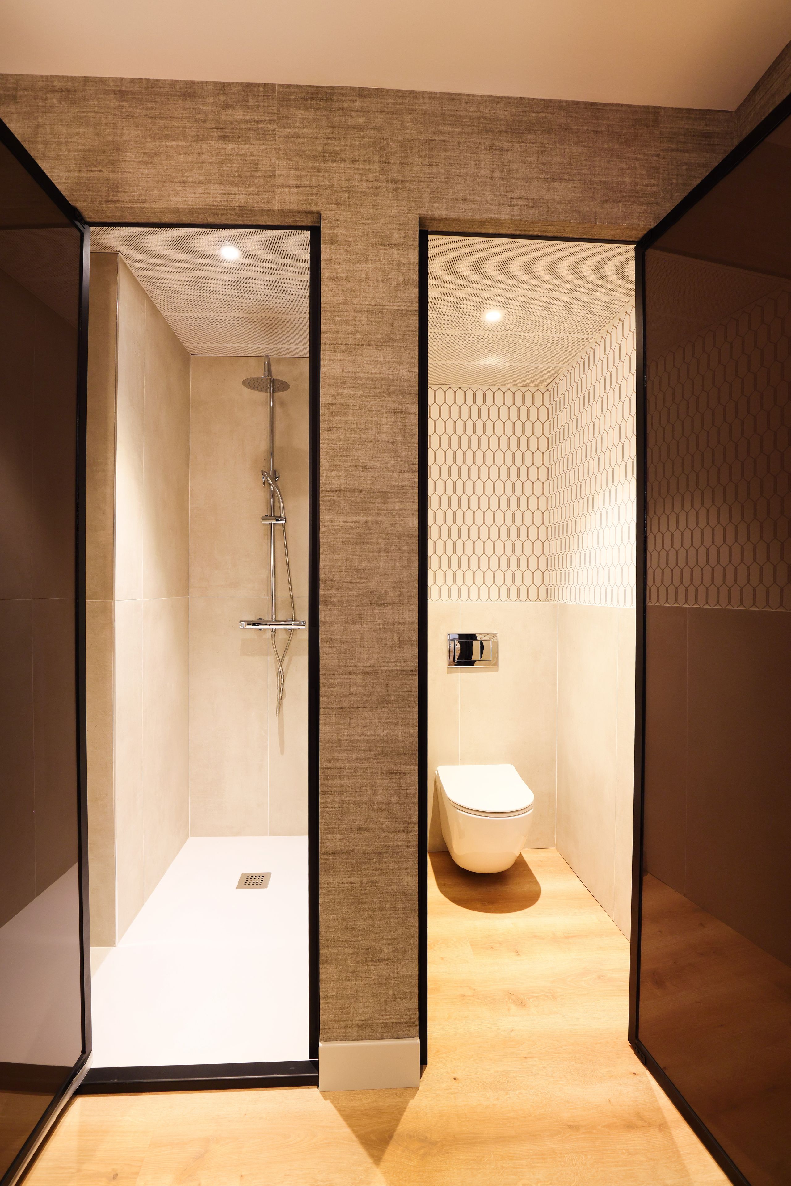 A modern bathroom with a shower, toilet, and a mirror.