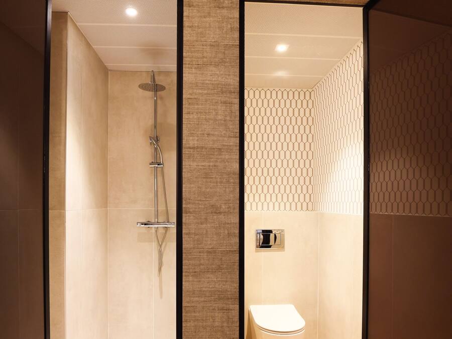 A modern bathroom with a shower, toilet, and a mirror.
