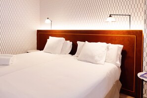 A hotel room with a neatly made bed, a headboard with a wooden finish, and a patterned wall. - THE Apartment by Assethoteles (Torrejón de Ardoz)
