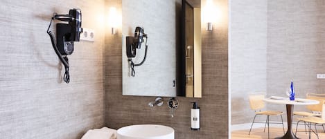 Un baño moderno con un espejo grande, dos secadores de pelo, un lavabo y una toalla.