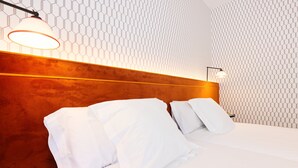 A hotel room with a wooden headboard, white bedding, and a hexagonal patterned wall. - THE Apartment by Assethoteles (Torrejón de Ardoz)