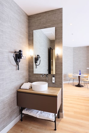 Uma casa de banho moderna com um espelho grande, uma pia e um secador de cabelo fixado na parede.
