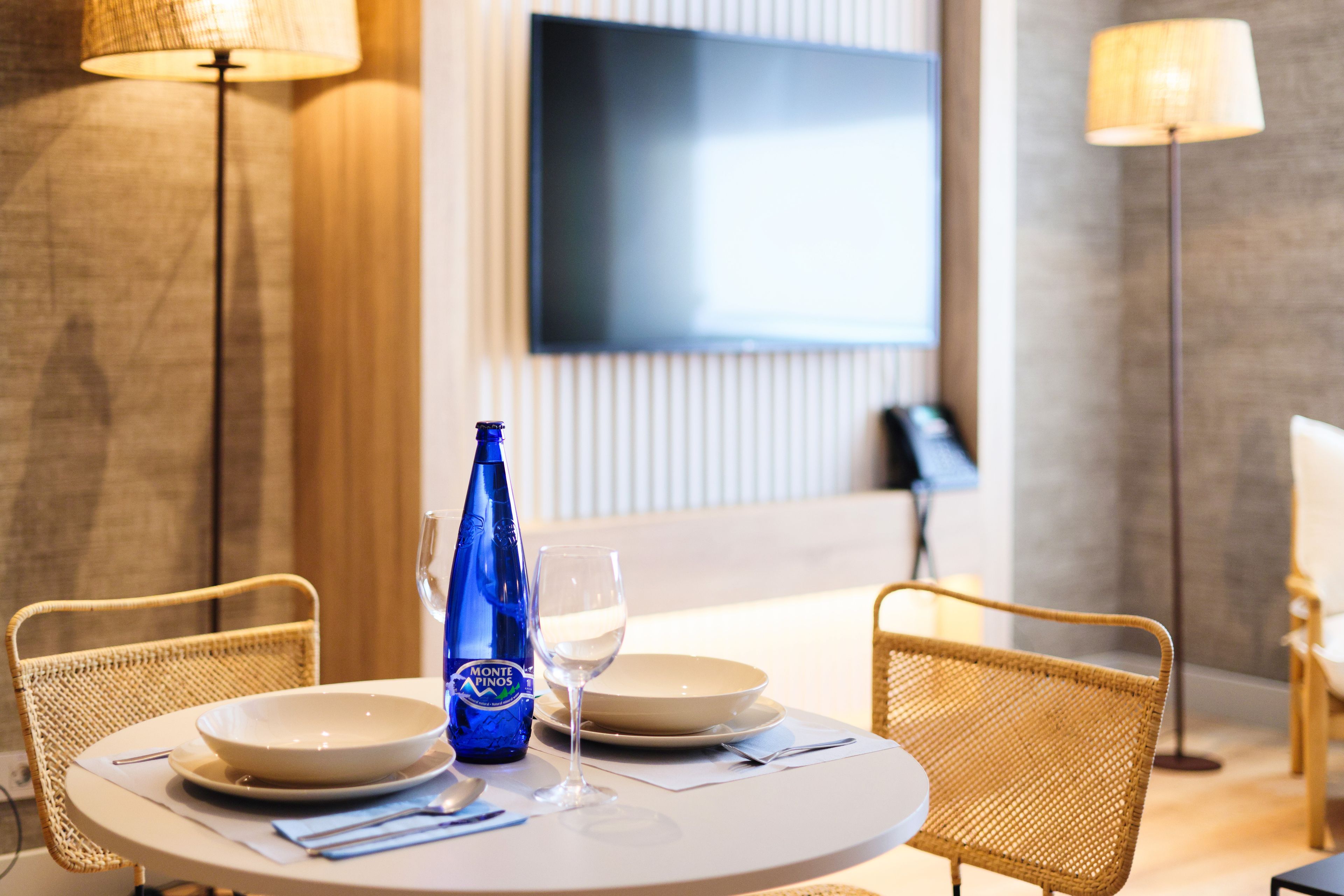 A dining table with two chairs, a bottle, and a glass.
