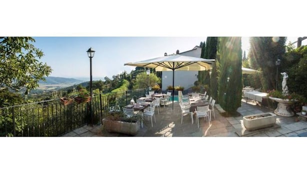 An outdoor patio area with tables and chairs, surrounded by greenery and a view of the landscape. - Classic Double with panoramic view (Toscana)