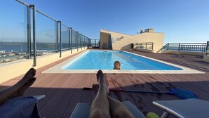 Ein Poolbereich mit freiem Blick auf das Meer, eine Liege und ein Schwimmbecken.