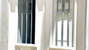 Eine weiße Tür mit einem Metallgitter und einem Fenster mit schmiedeeisernen Gitterstäben.