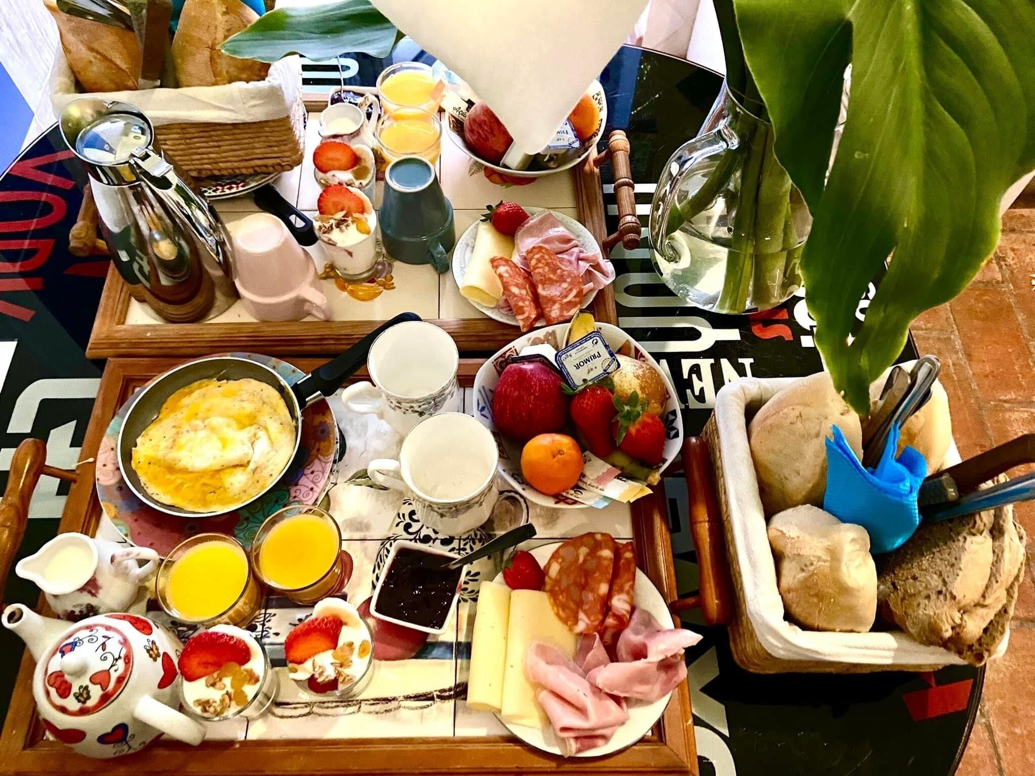A breakfast tray with various foods and drinks, including eggs, fruits, cheese, and meats.