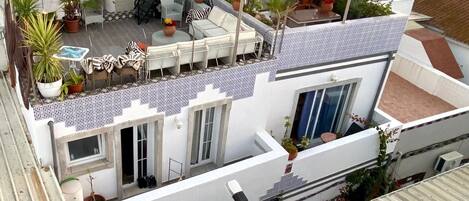 Terraza en la azotea con escaleras, zona de estar y plantas en macetas.