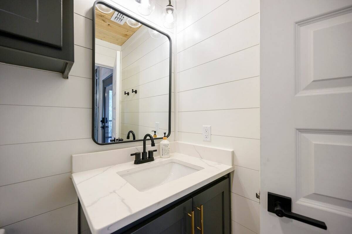 A bathroom with a white sink, black faucet, and a mirror above it.