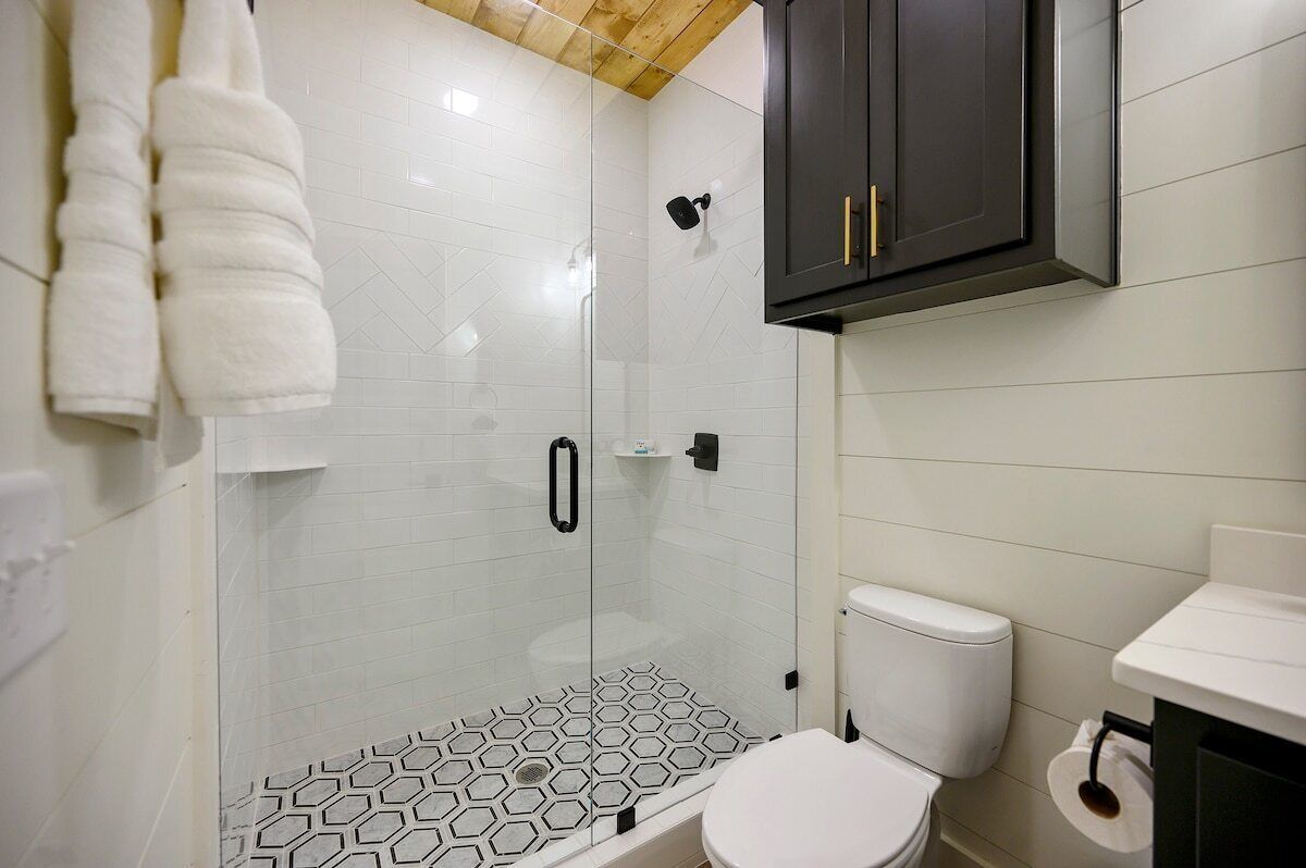 A bathroom with a glass shower enclosure, a toilet, and a sink.