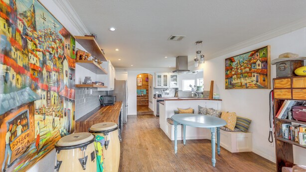 A kitchen with wooden cabinets, a dining table, and a view into the living area. - Pet-Friendly Austin Home w/ Private Yard + Deck! (Austin)