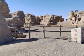 A desert landscape with rock formations and a wooden fence. - Jiulong Holiday Hotel (Hami)