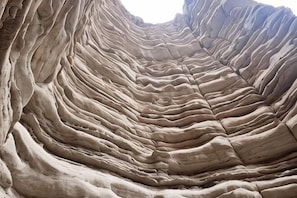 A rock formation with layered textures and a narrow passageway. - Jiulong Holiday Hotel (Hami)