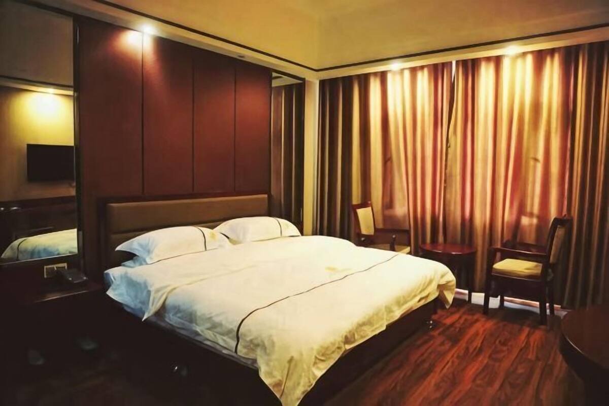 Une chambre d’hôtel avec un grand lit, une chaise, un bureau et une télévision.