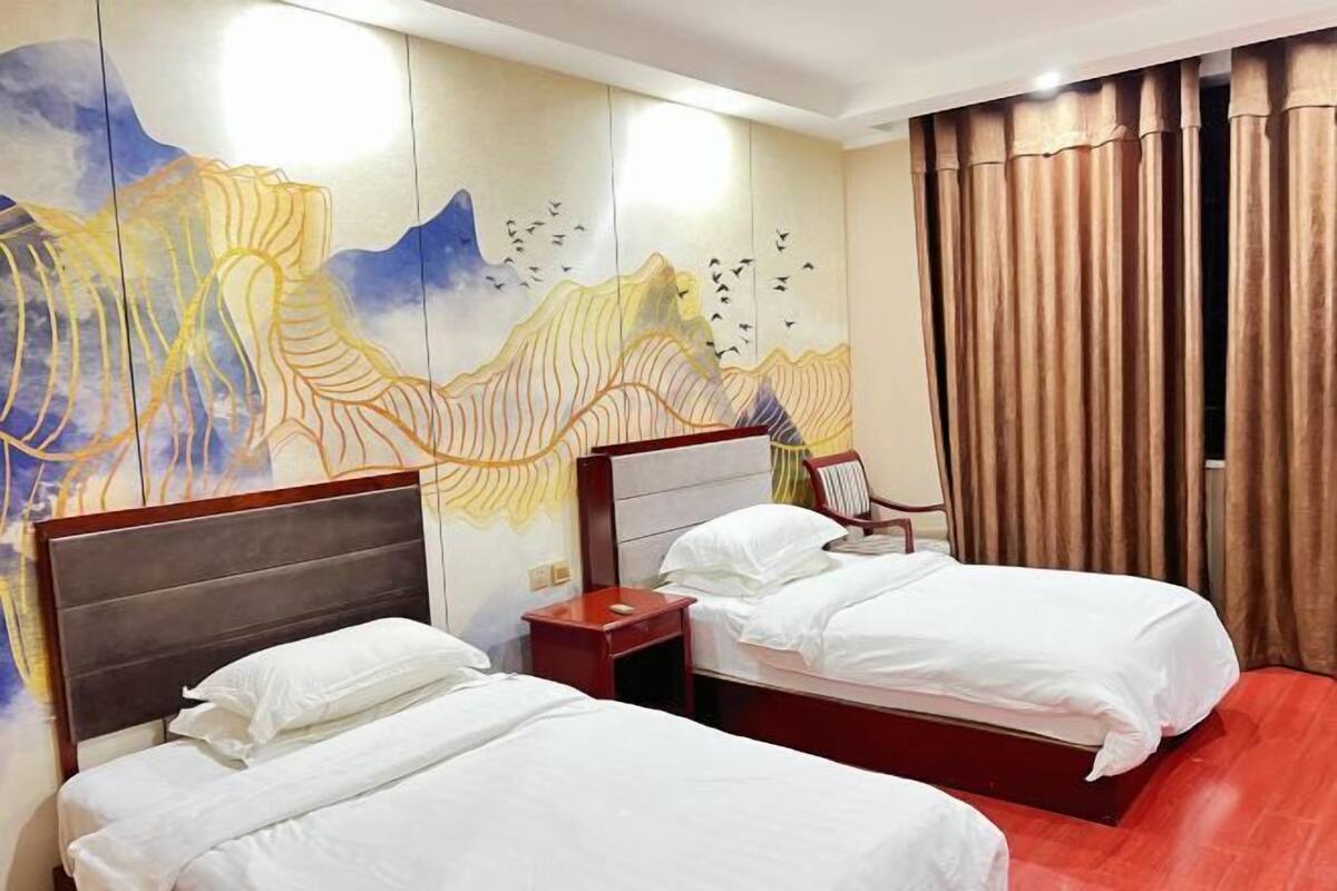 Une chambre d’hôtel avec deux lits, une tête de lit en bois, une table de chevet et une fresque murale.
