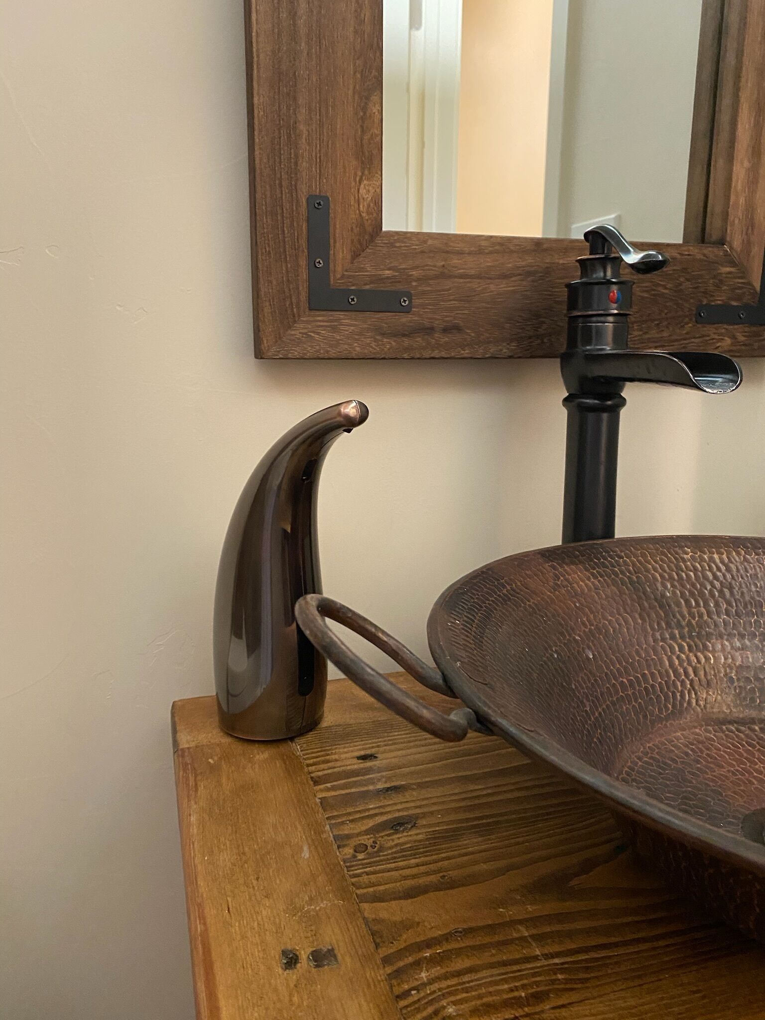 Un plan de travail en bois avec un évier et un robinet en métal, un tabouret en bois et un miroir avec un cadre en bois.