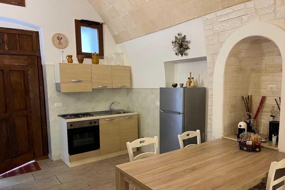 Una cocina compacta con comedor, estufa, horno, refrigerador y un ventanal.