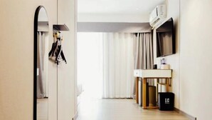 A hotel room with a mirror, a desk, a TV, and a suitcase. - Shanghai Jincheng Hotel (Zhujiajiao Ancient Town) (Shanghai)