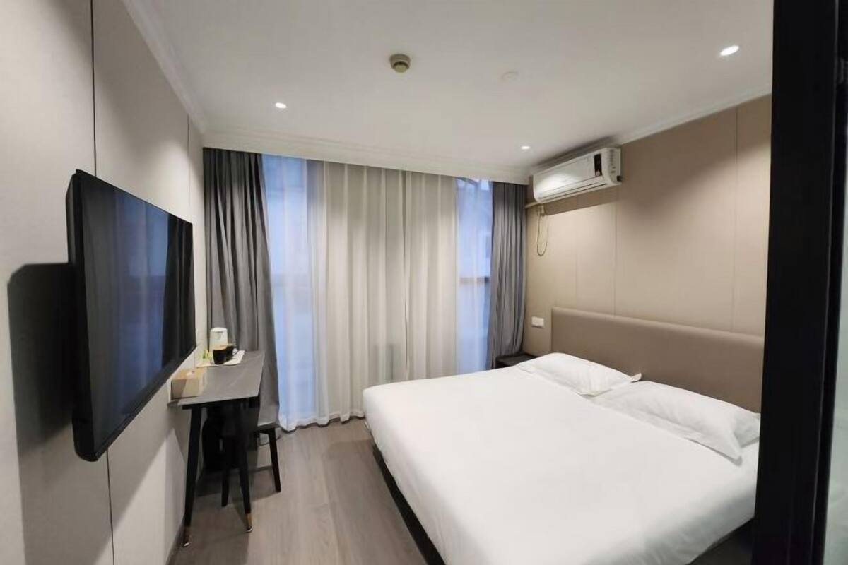 Une chambre d’hôtel équipée d’un lit, d’un bureau, d’une chaise, d’une télévision et d’un appareil de climatisation.