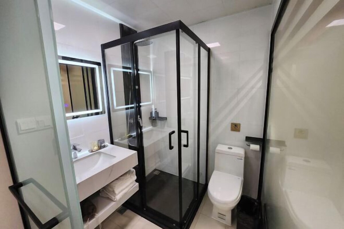 A modern bathroom with a glass-enclosed shower, a white sink, and a toilet.
