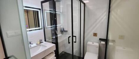 A modern bathroom with a glass-enclosed shower, a white sink, and a toilet.