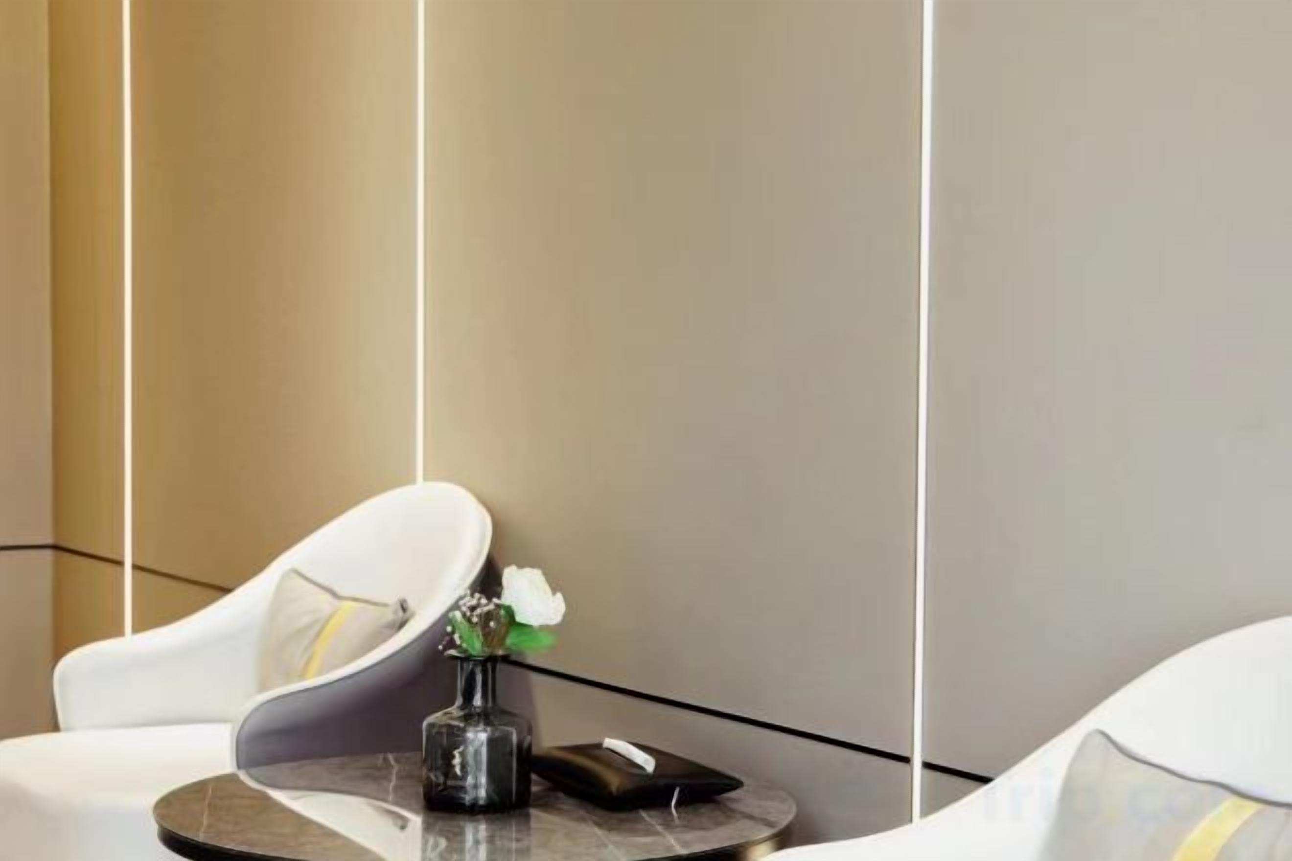 A modern hotel room with a round table, a white chair, and a vase with flowers.