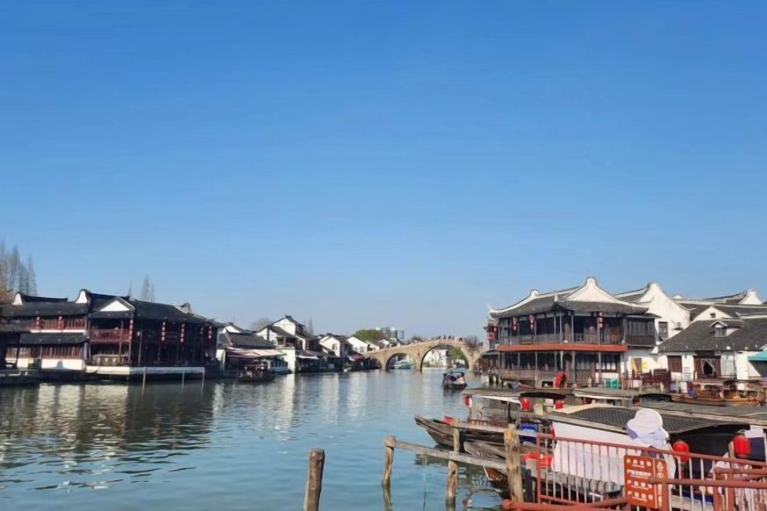 Vista a la orilla del río con edificios tradicionales, un puente y barcos.