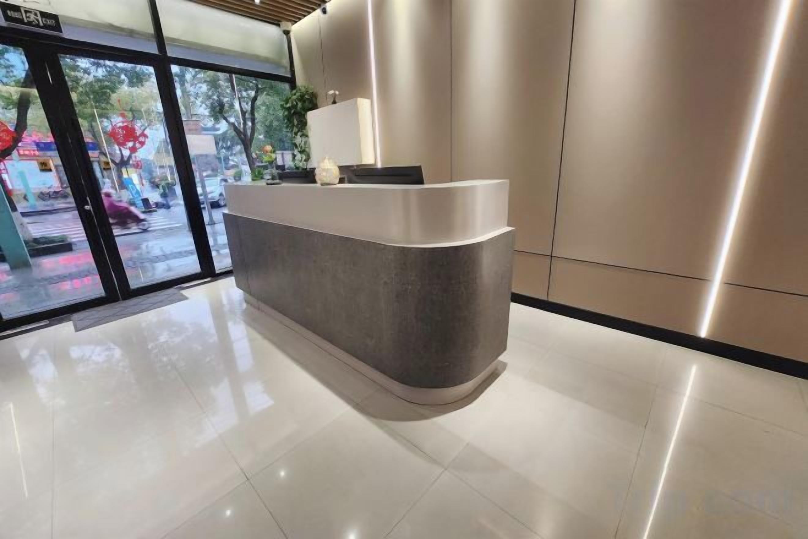 Un mostrador de recepción con entrada por puerta de vidrio, una planta en la encimera y un diseño interior moderno.