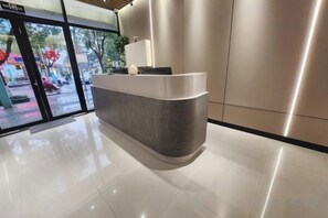 A reception desk with a glass door entrance, a plant on the counter, and a modern interior design. - Shanghai Jincheng Hotel (Zhujiajiao Ancient Town) (Shanghai)
