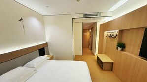 A hotel room with a large bed, a wooden bench, a small table, and a wall-mounted TV. - Shanghai Jincheng Hotel (Zhujiajiao Ancient Town) (Shanghai)