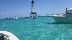 A clear turquoise sea with a lighthouse in the distance and several boats. - Keys Paradise! (Key Largo)