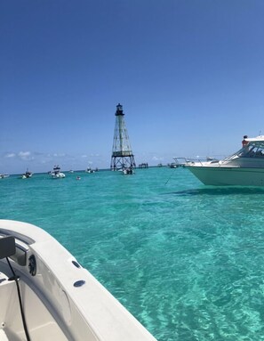 A clear turquoise sea with a lighthouse in the distance and several boats. - Keys Paradise! (Key Largo)