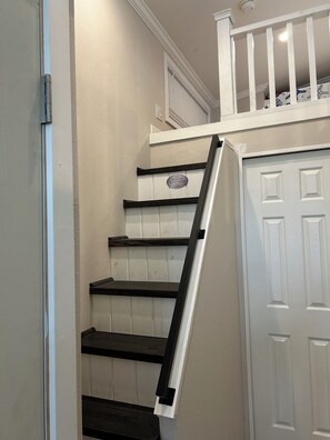 A staircase with a handrail, a white door, and a sign that reads 'Remove Your Shoes'.