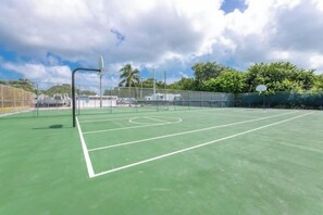 A tennis court with a net, surrounded by a fence and trees. - Keys Paradise! (Key Largo)