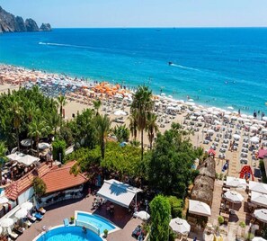 Un resort en la playa con piscina, sombrillas y sillas.
