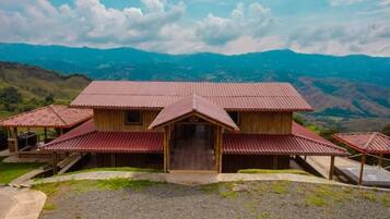 Un bâtiment en bois avec un toit rouge, entouré d’un paysage montagneux.