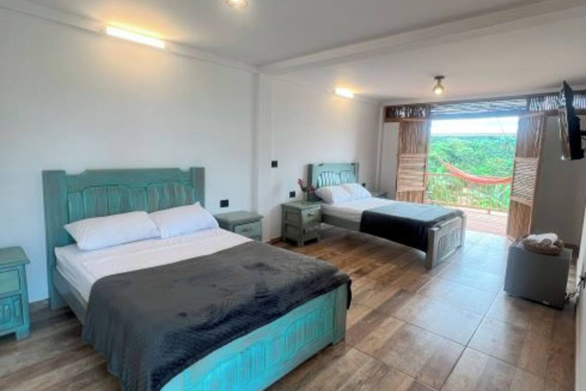 Ein Schlafzimmer mit zwei Betten, einem großen Fenster mit Blick und einem kleinen Balkon.