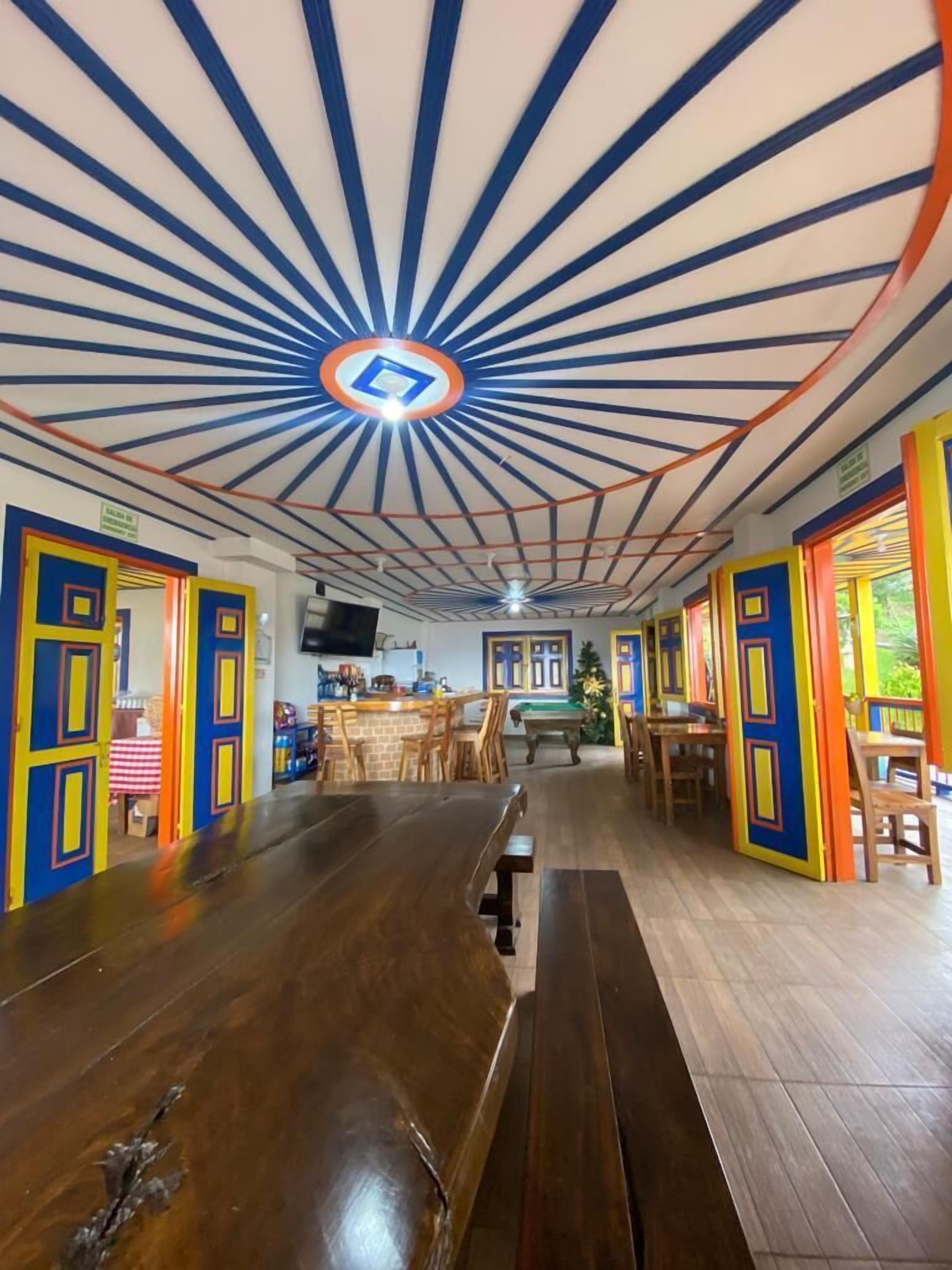 A spacious room with a long wooden bench, a pool table, and a ceiling with radial beams.
