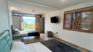 A bedroom with a bed, a sofa, a TV, and a window with blinds. - Hotel Terra Belén (Belén de Umbría)