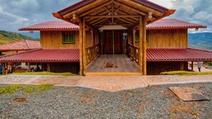 A wooden house with a central entrance and two wings, set against a mountainous backdrop. - Hotel Terra Belén (Belén de Umbría)