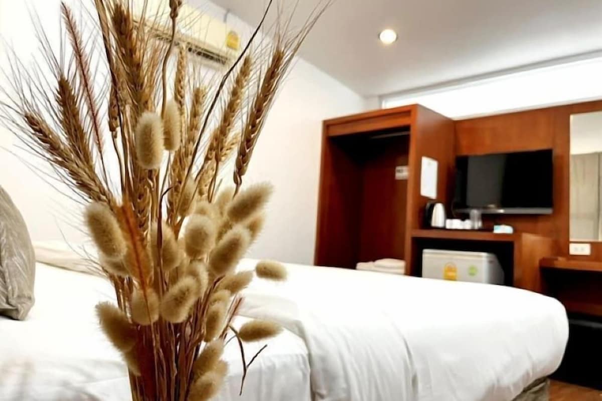 A hotel room with a bed, a television, and a wooden cabinet.