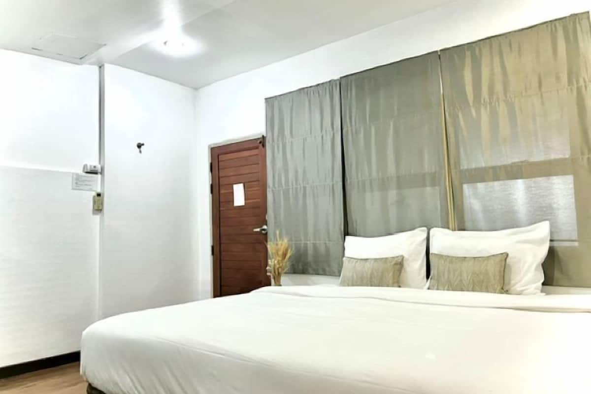 Un dormitorio con cama, una puerta y una ventana con cortinas.
