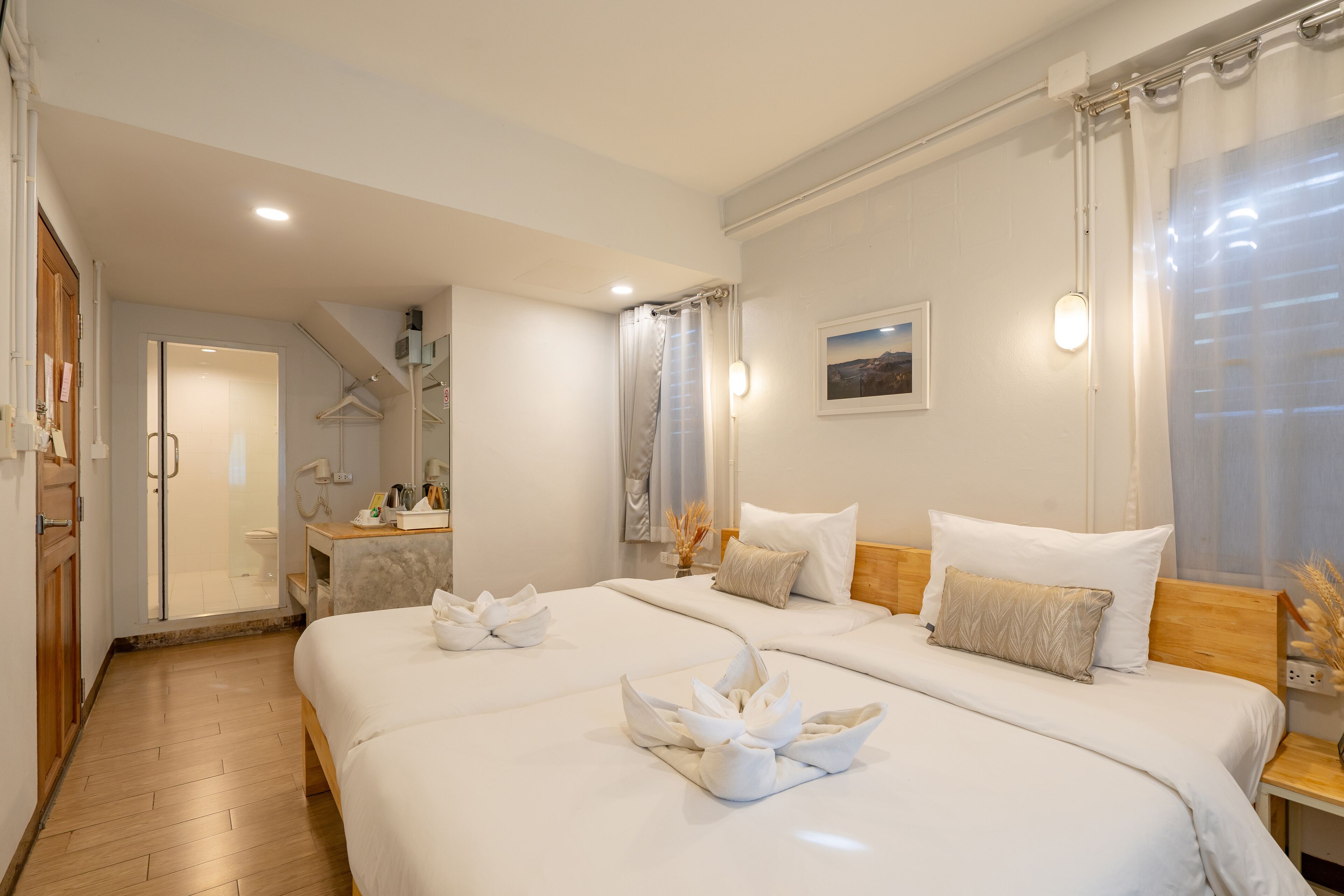 A hotel room with two beds, a bathroom, and a shower area.