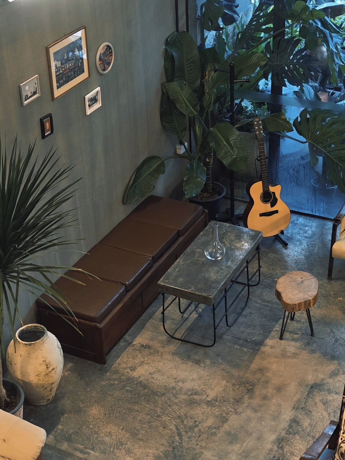 A cozy room with a sofa, a small table, a guitar, and various framed pictures on the wall.