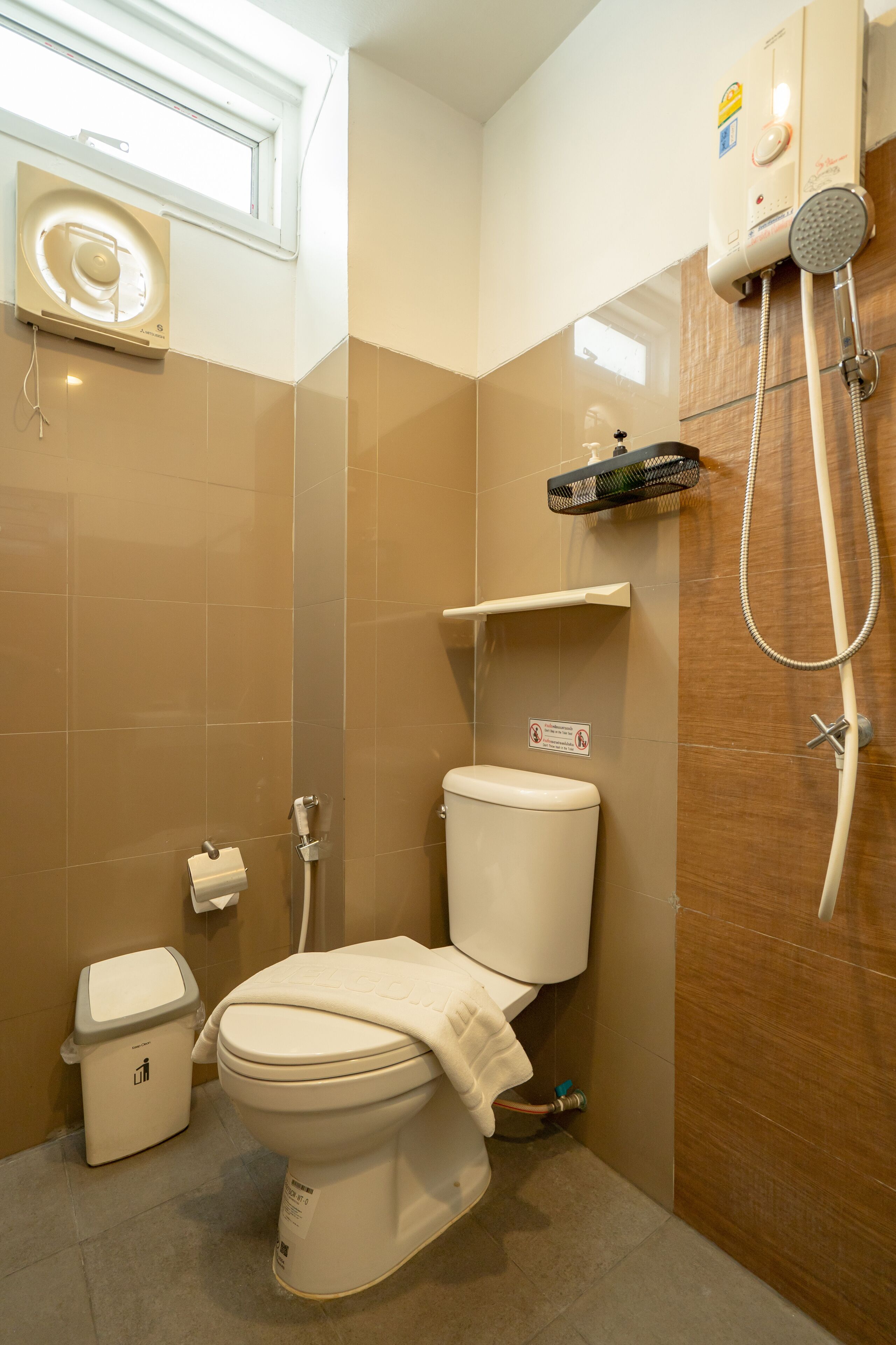 A bathroom with a toilet, a shower, a hand dryer, and a towel rack.