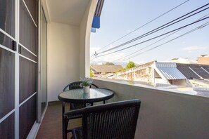 Ein Balkon mit Tisch und Stühlen, einem Blumentopf und Blick auf Gebäude sowie Solaranlagen.