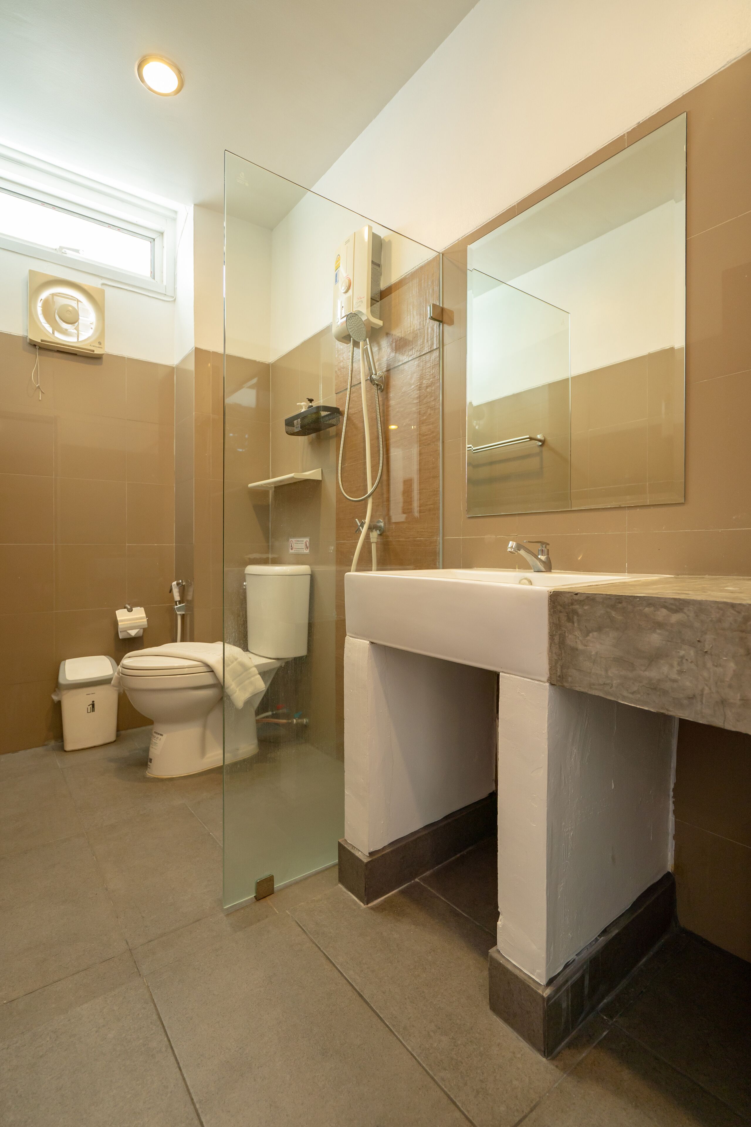A modern bathroom with a glass shower enclosure, a toilet, and a sink with a large mirror above it.