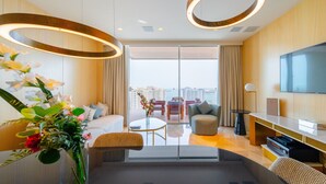 A modern hotel room with a large window, a flat-screen TV, a sofa, a coffee table, and a decorative vase with flowers. - Fascinating 1BR with Burj Arab View at FIVE Palm (Dubai)